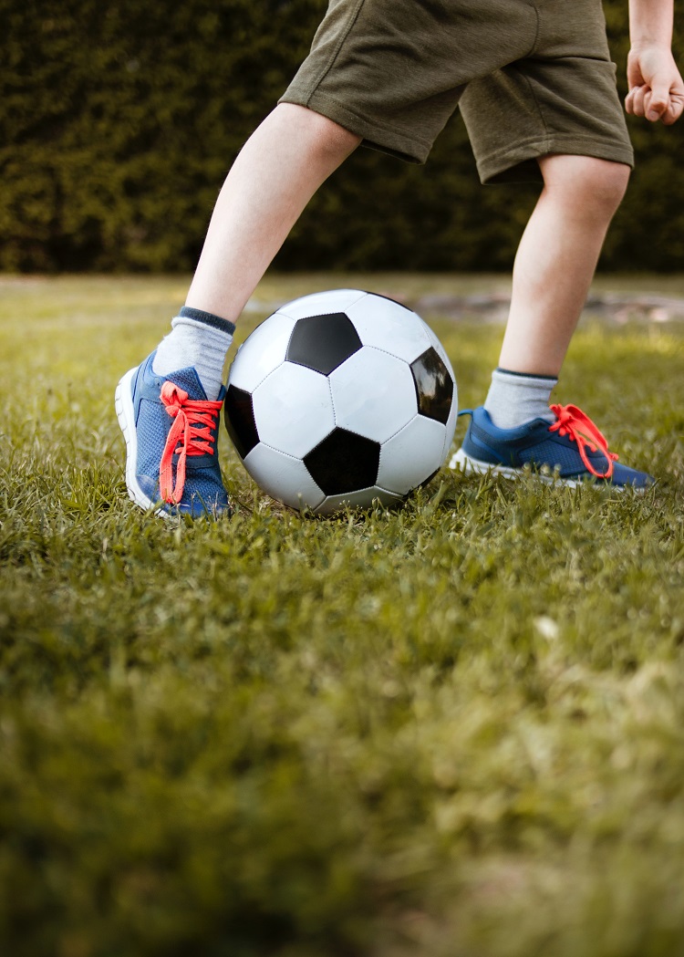 child playing football with sports sneakers