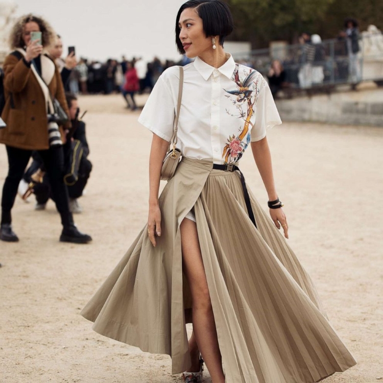 woman wearing beige maxi skirt with black belt, white t-shirt and beige bag
