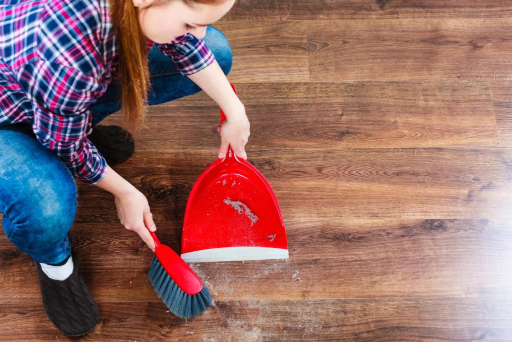 kid cleaning with red broom and red dustpan on floor