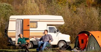 a couple sitting next to a camper